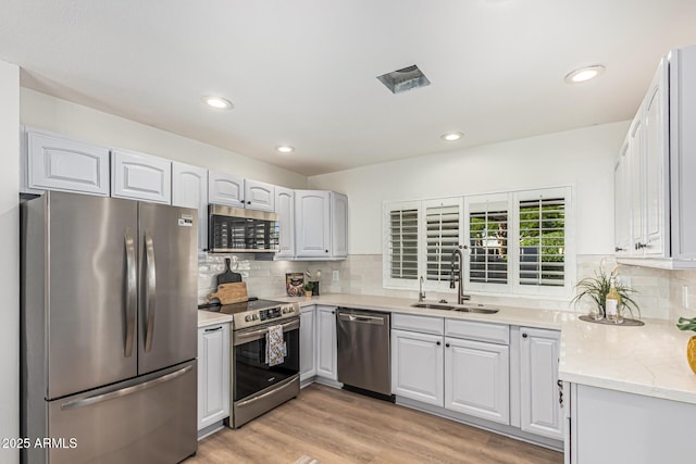 5333 E Sheena Dr, Scottsdale, AZ 85254 - kitchen featuring appliances with stainless steel finishes, a sink, decorative backsplash, light wood-style flooring, and light stone countertops