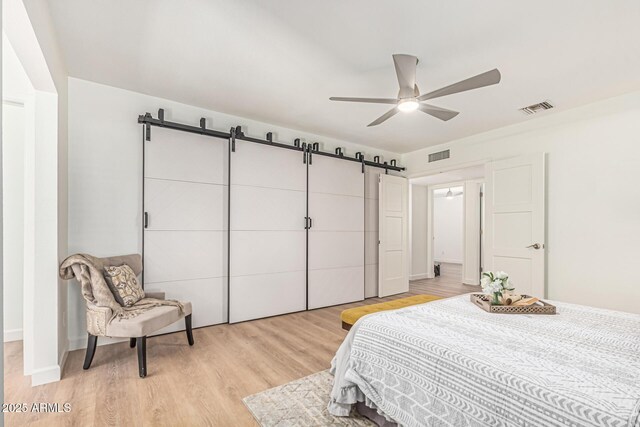 5333 E Sheena Dr, Scottsdale, AZ 85254 - bedroom featuring a barn door, light wood-style floors, and ceiling fan