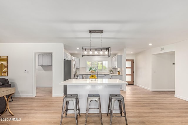 5333 E Sheena Dr, Scottsdale, AZ 85254 - kitchen with light countertops, a breakfast bar, light wood-type flooring, baseboards, and recessed lighting