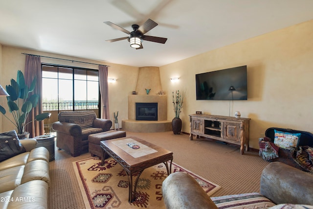 living room featuring ceiling fan, carpet flooring, and a large fireplace