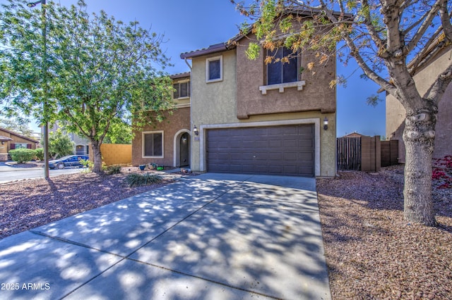 view of front of house with an attached garage, concrete driveway, stucco siding, and fence