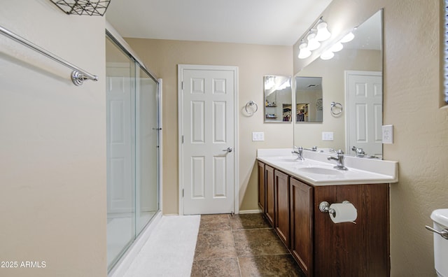 full bathroom featuring a sink, toilet, double vanity, and a stall shower