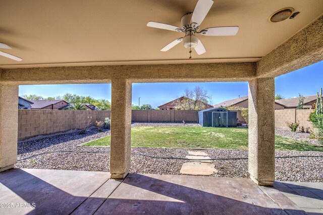 view of patio featuring an outbuilding, a shed, a fenced backyard, and a ceiling fan