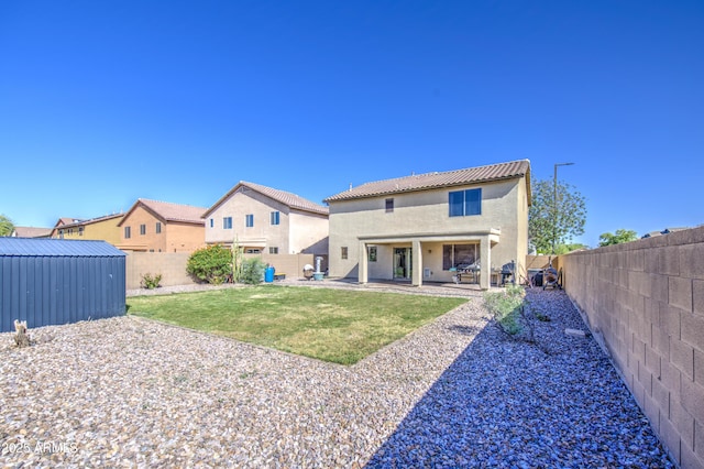 rear view of house with a fenced backyard, stucco siding, a patio area, and a lawn
