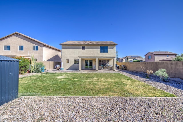 rear view of house with a lawn, a fenced backyard, a tile roof, a patio, and stucco siding