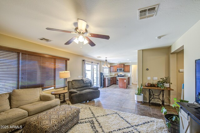 tiled living room with ceiling fan, baseboards, and visible vents