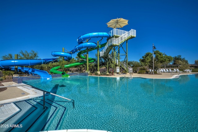 pool with a water slide, a patio, and stairway