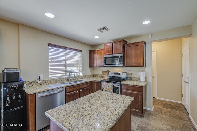 kitchen featuring visible vents, a center island, a sink, stainless steel appliances, and baseboards
