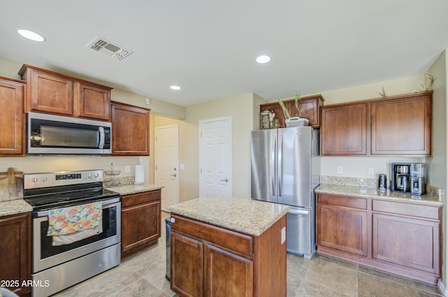kitchen featuring visible vents, appliances with stainless steel finishes, a kitchen island, and light stone countertops