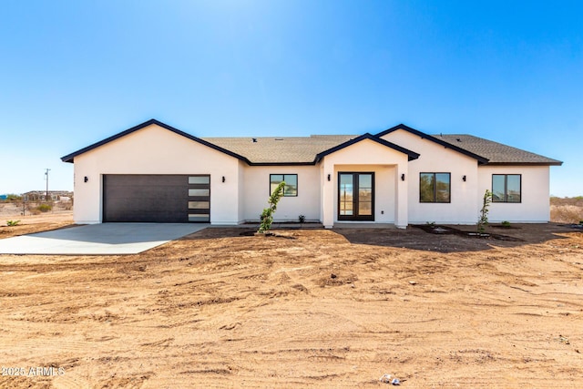 modern farmhouse style home with a garage, french doors, driveway, and stucco siding