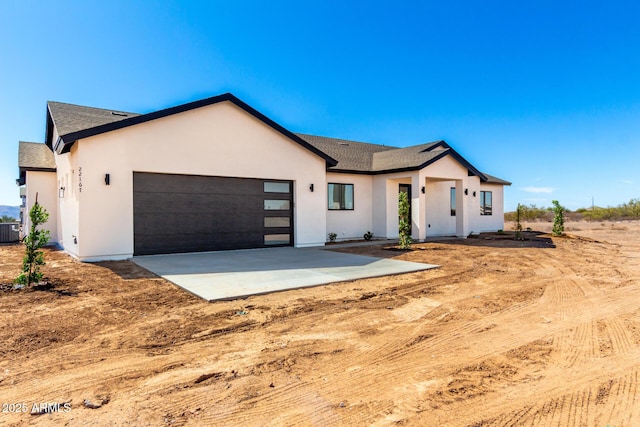 view of front of house with cooling unit, driveway, an attached garage, and stucco siding