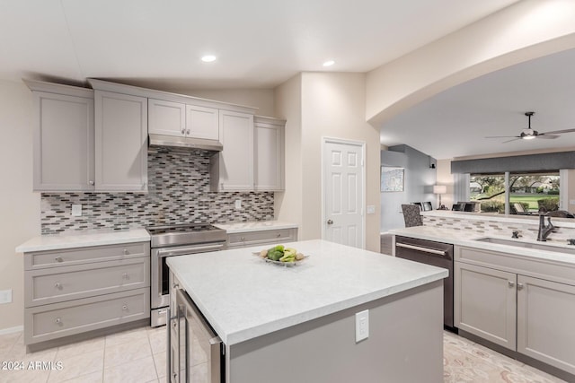 kitchen with sink, appliances with stainless steel finishes, a center island, and lofted ceiling