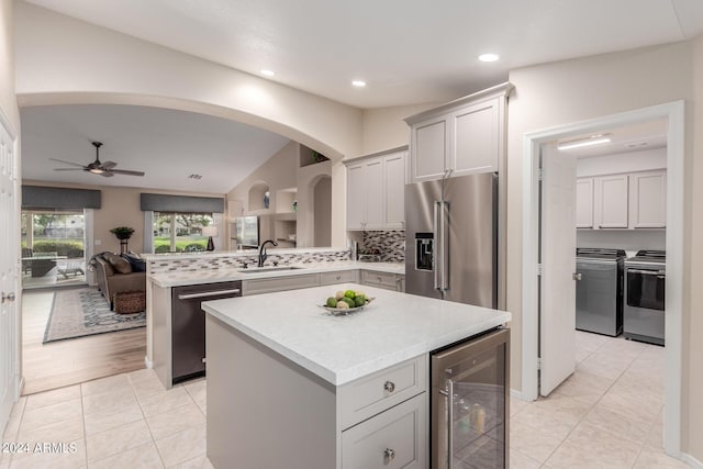 kitchen featuring appliances with stainless steel finishes, sink, a kitchen island, backsplash, and wine cooler