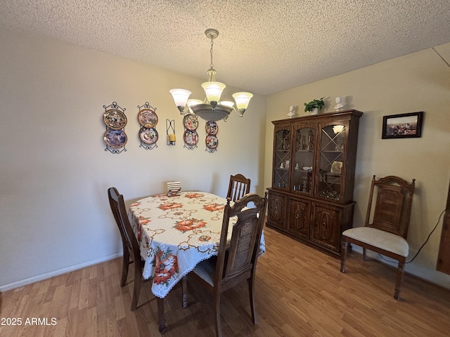 dining space featuring a chandelier, a textured ceiling, and hardwood / wood-style flooring