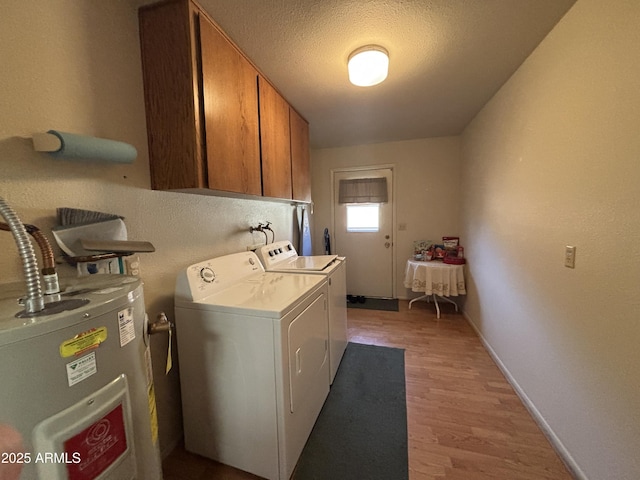 washroom with washer and clothes dryer, cabinets, a textured ceiling, water heater, and light hardwood / wood-style floors