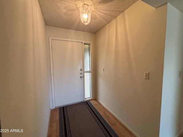 doorway to outside with wood-type flooring and a textured ceiling