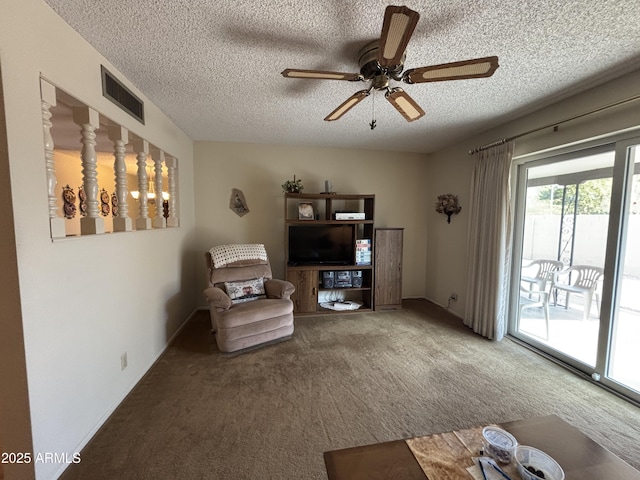 living area featuring carpet flooring, a textured ceiling, and ceiling fan