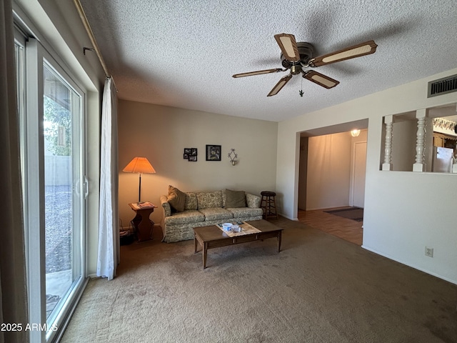 living room with ceiling fan, light colored carpet, and a textured ceiling