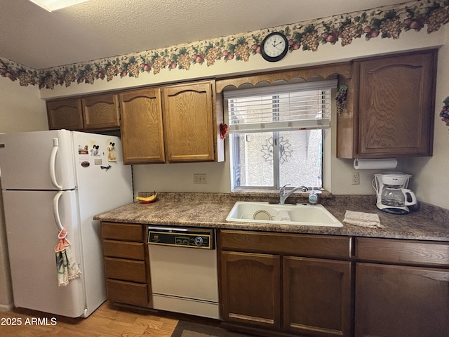 kitchen with a textured ceiling, white appliances, light hardwood / wood-style flooring, and sink