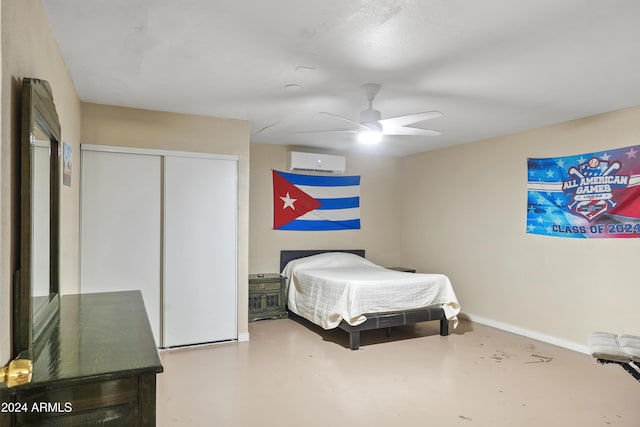 bedroom with ceiling fan, a closet, an AC wall unit, and concrete floors