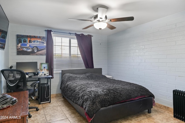 bedroom with light tile patterned flooring, ceiling fan, radiator, and brick wall