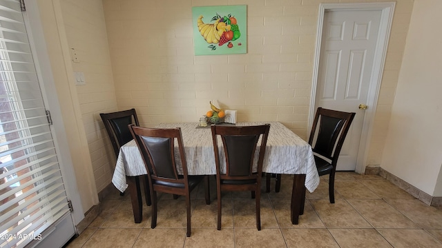 tiled dining space featuring brick wall