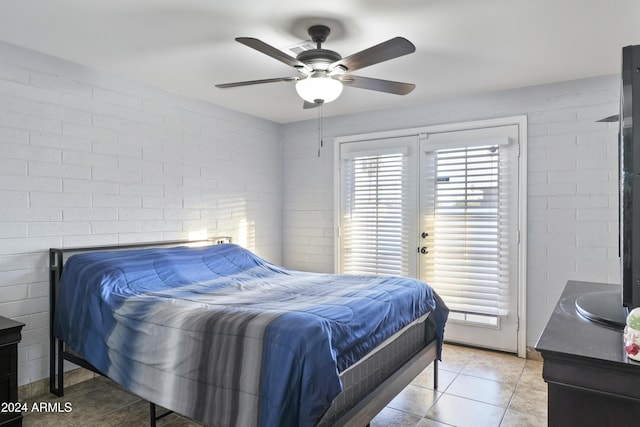 tiled bedroom featuring ceiling fan and brick wall