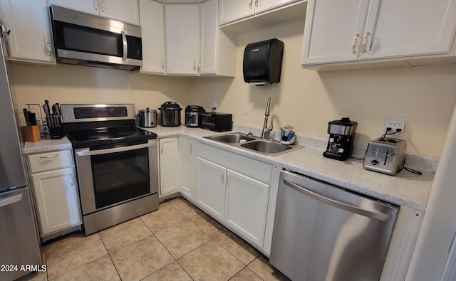 kitchen featuring white cabinets, appliances with stainless steel finishes, light tile patterned floors, and sink