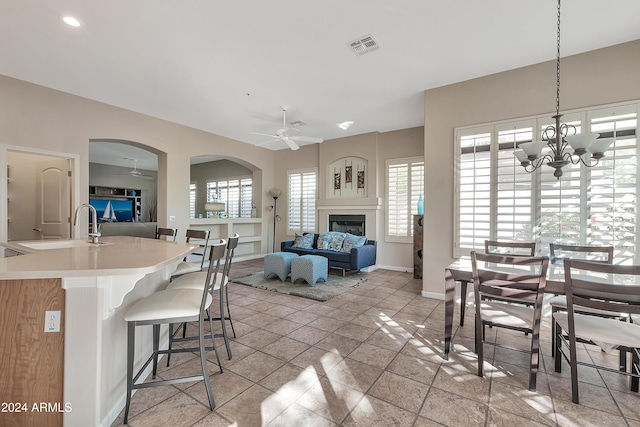 dining area with ceiling fan with notable chandelier and sink