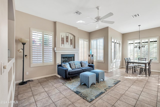 tiled living room with ceiling fan with notable chandelier and plenty of natural light