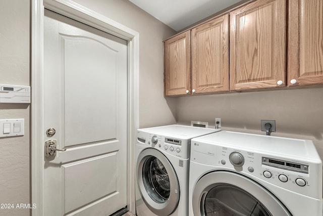 washroom featuring washing machine and clothes dryer and cabinets