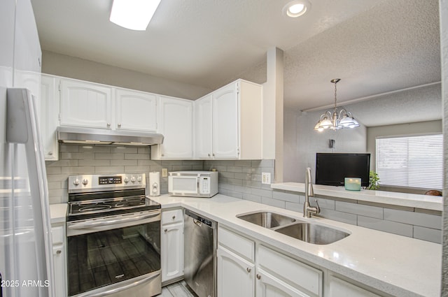 kitchen featuring appliances with stainless steel finishes, decorative light fixtures, white cabinetry, an inviting chandelier, and sink