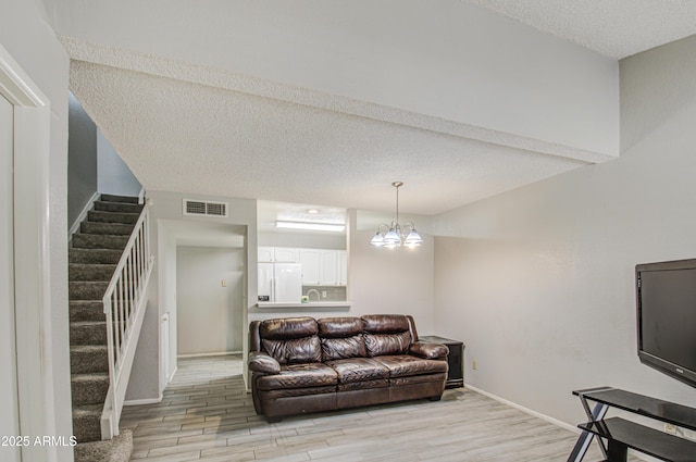 living room featuring a textured ceiling, light hardwood / wood-style flooring, and a notable chandelier