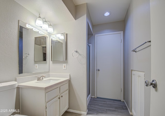 bathroom with hardwood / wood-style flooring, toilet, vanity, and a shower with door