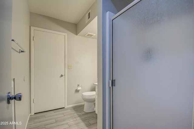 bathroom featuring a shower with shower door and toilet