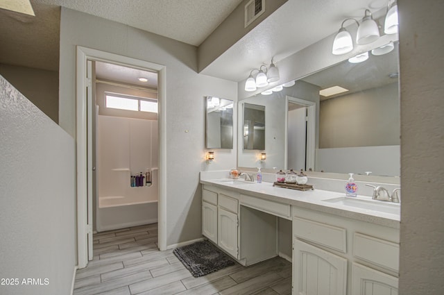 bathroom featuring a textured ceiling, an inviting chandelier, and vanity