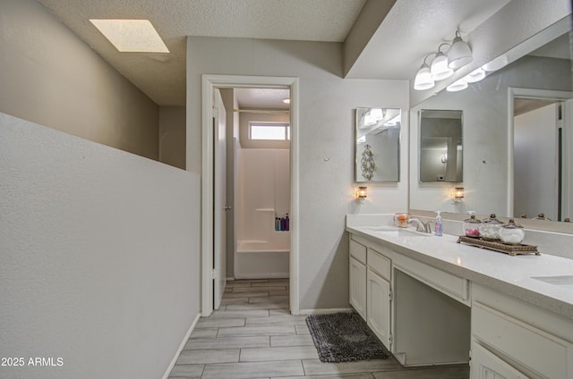 bathroom with a textured ceiling, a skylight, wood-type flooring, and vanity