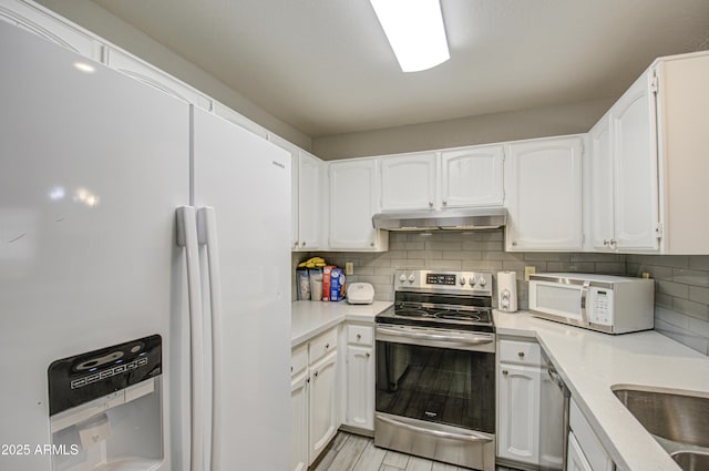 kitchen with tasteful backsplash, white cabinets, and appliances with stainless steel finishes