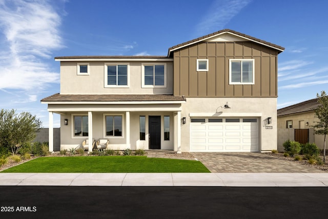 view of front of property featuring decorative driveway, stucco siding, board and batten siding, a front yard, and a garage