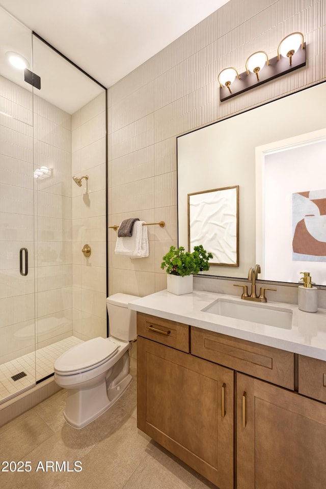 full bath featuring toilet, tile walls, vanity, a shower stall, and tile patterned floors