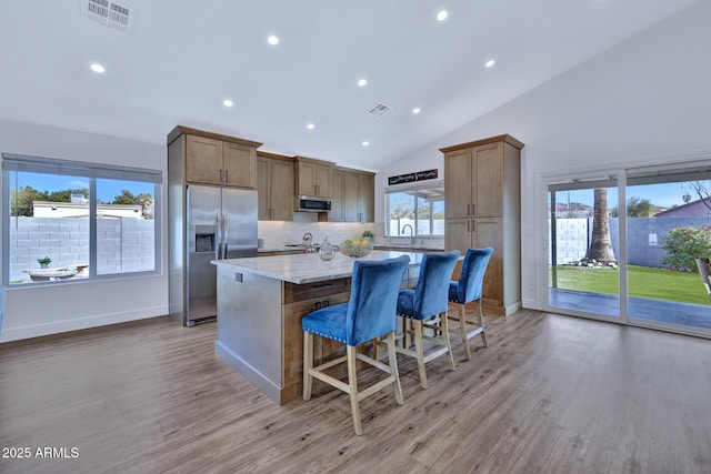 kitchen featuring stainless steel appliances, light stone countertops, a center island, and light hardwood / wood-style floors