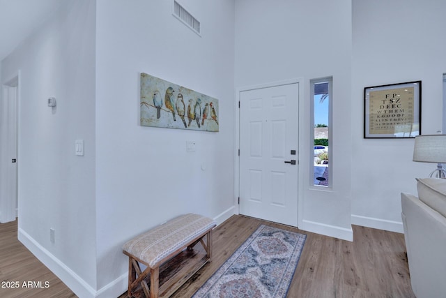 foyer entrance with a towering ceiling and light hardwood / wood-style floors