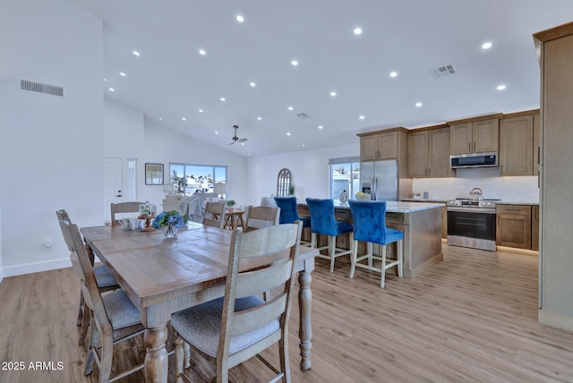 dining space featuring a towering ceiling and light hardwood / wood-style flooring