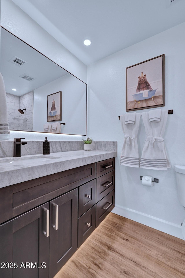 bathroom featuring hardwood / wood-style flooring, vanity, and tiled shower