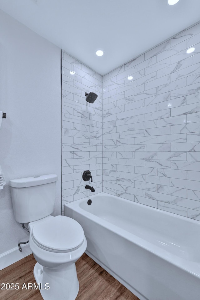 bathroom featuring tiled shower / bath, wood-type flooring, and toilet