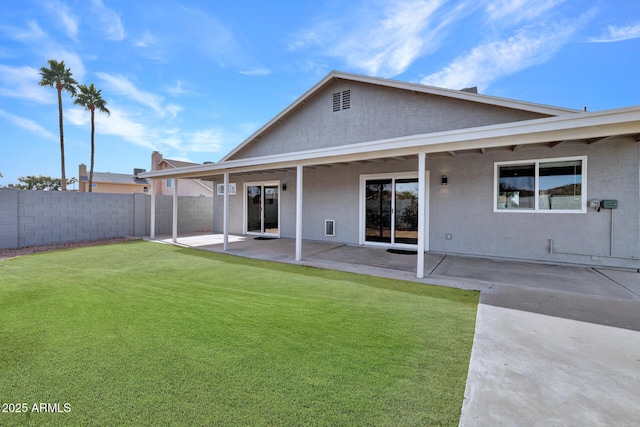 rear view of house featuring a lawn and a patio