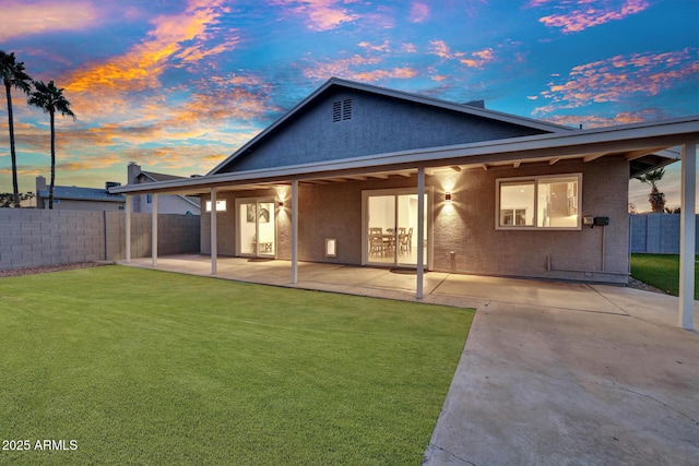 back house at dusk with a yard and a patio area