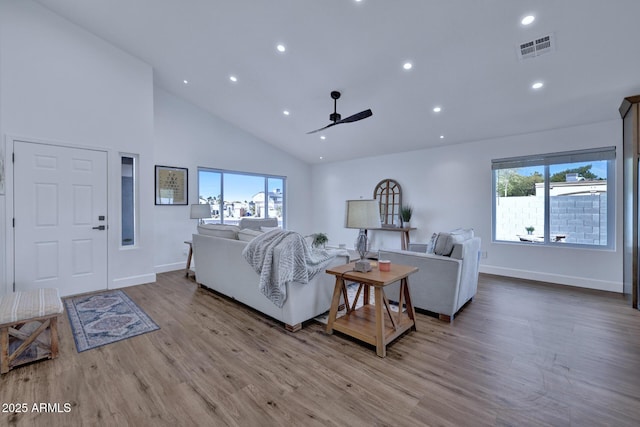 living room with ceiling fan, high vaulted ceiling, and light hardwood / wood-style floors