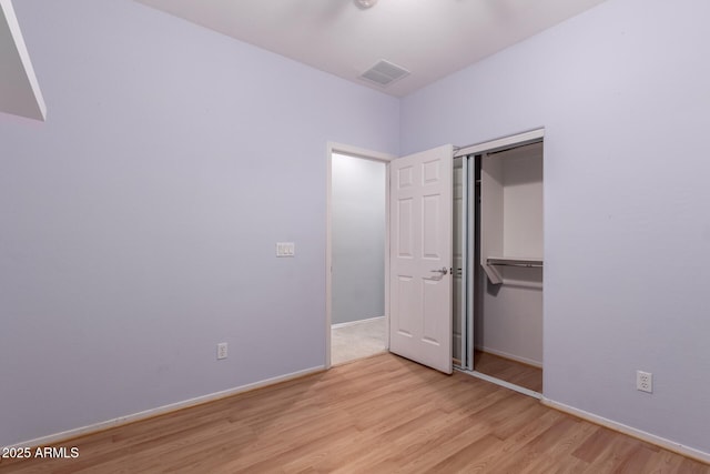 unfurnished bedroom featuring light wood-type flooring, visible vents, baseboards, and a closet