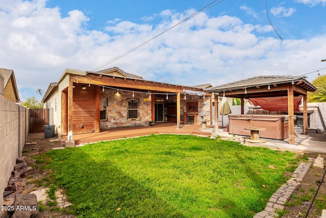 rear view of property featuring a hot tub, a gazebo, a yard, a fenced backyard, and a patio